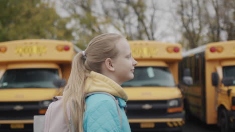 A-student-walks-along-a-row-of-yellow-school-buses