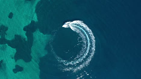 Von-Oben-Nach-Unten-Kamerafahrt-Eines-Motorbootes,-Das-An-Einem-Sonnigen-Tag-Durch-Das-Meer-Fährt