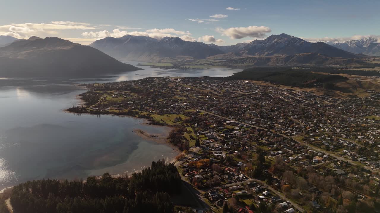 Ampia veduta aerea panoramica della città di Wanaka sul lungolago con catena montuosa delle Alpi meridionali innevate sullo sfondo, Nuova Zelanda