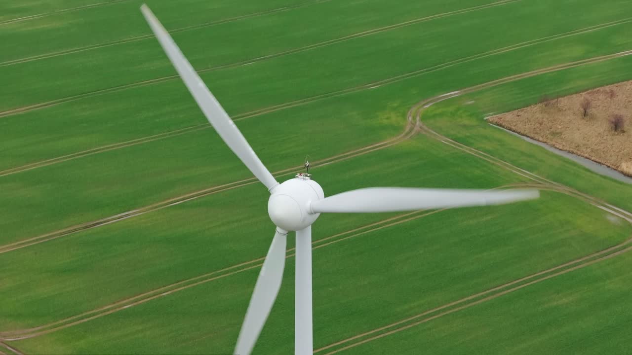 Movimento cinematico a inclinazione che rivela un generatore eolico su un terreno agricolo serale nuvoloso