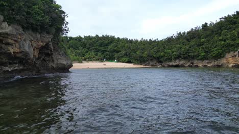 Aerial,-Rising-shot-of-secret-white-sand-beach-resort-with-stunning-clear-waters-and-palm-trees-in-Catanduanes,-Philippines