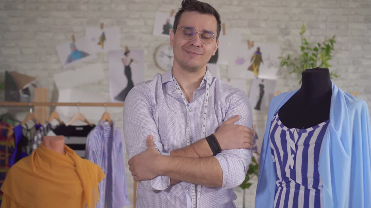 retrato de hombre diseñador de moda en gafas en un estudio moderno al lado de un maniquí y con una cinta de medición
