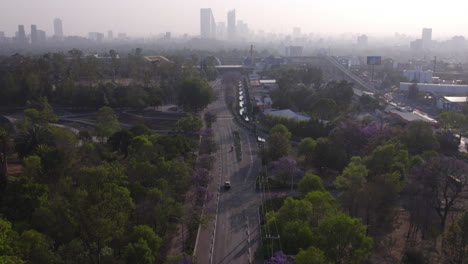 Aerial-view-capital-city-of-Mexico,-park-Bosque-de-Chapultepec-and-city-center-skyline-with-modern-high-rise-buildings---green-landscape-and-vehicles-driving