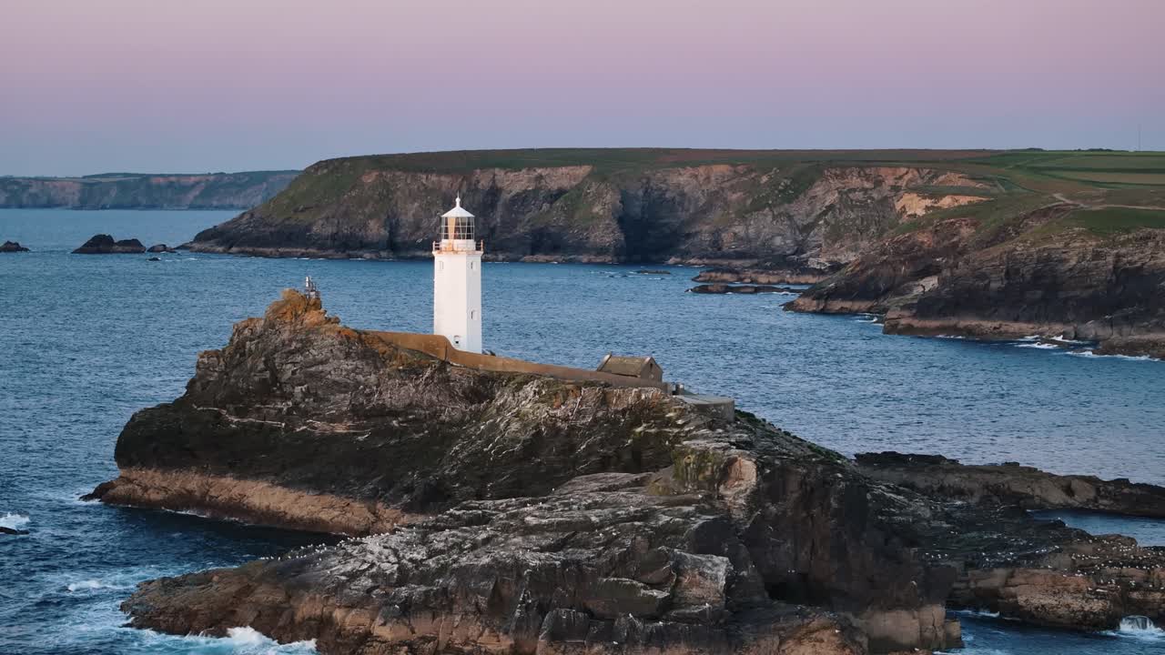 Aerial ascent over Godfrey’s Point Lighthouse showing rocks and deep water in scenic coastal view, establishing