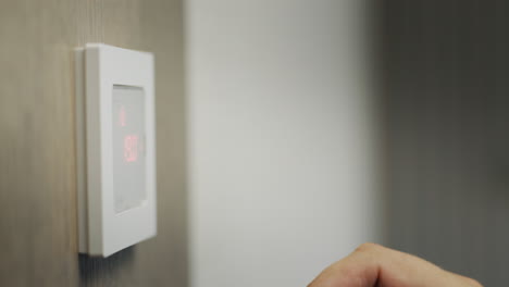 el propietario regula la temperatura de la casa en el panel de control electrónico