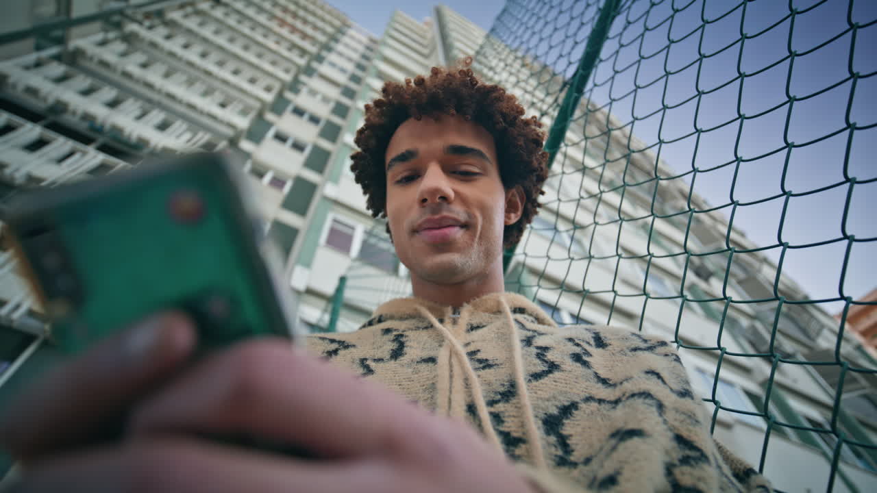 Happy zoomer chatting phone surrounded by cityscape closeup. Man reading message
