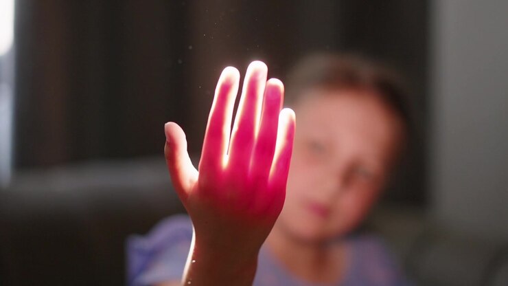 Ragazzina che gioca con la luce del sole tra le dita