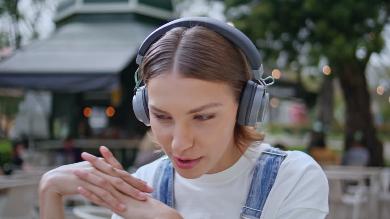 Hipster talking online conference in wireless earphones at street cafe closeup