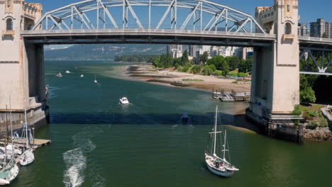 Aerial-View-Of-Sailboats-Passing-Under-Burrard-Street-Bridge-Over-False-Creek-With-Sunset-Beach-In-BC,-Canada