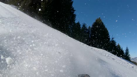 slow motion, a skier going down a steep slope, in the background a blue sky with bright sun and snow rising from the skis view from the skier’s back