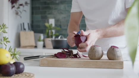 close-up of a man peeling fresh beetroot with a peeler in a modern kitchen