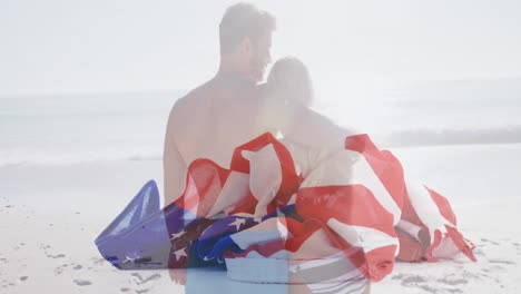 american flag falling against rear view of caucasian couple hugging on the beach