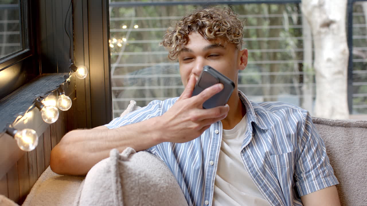 Relaxing at home, Asian man using smartphone for voice message by window