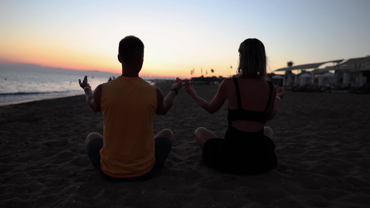 Couple Meditating on the Beach at Sunset