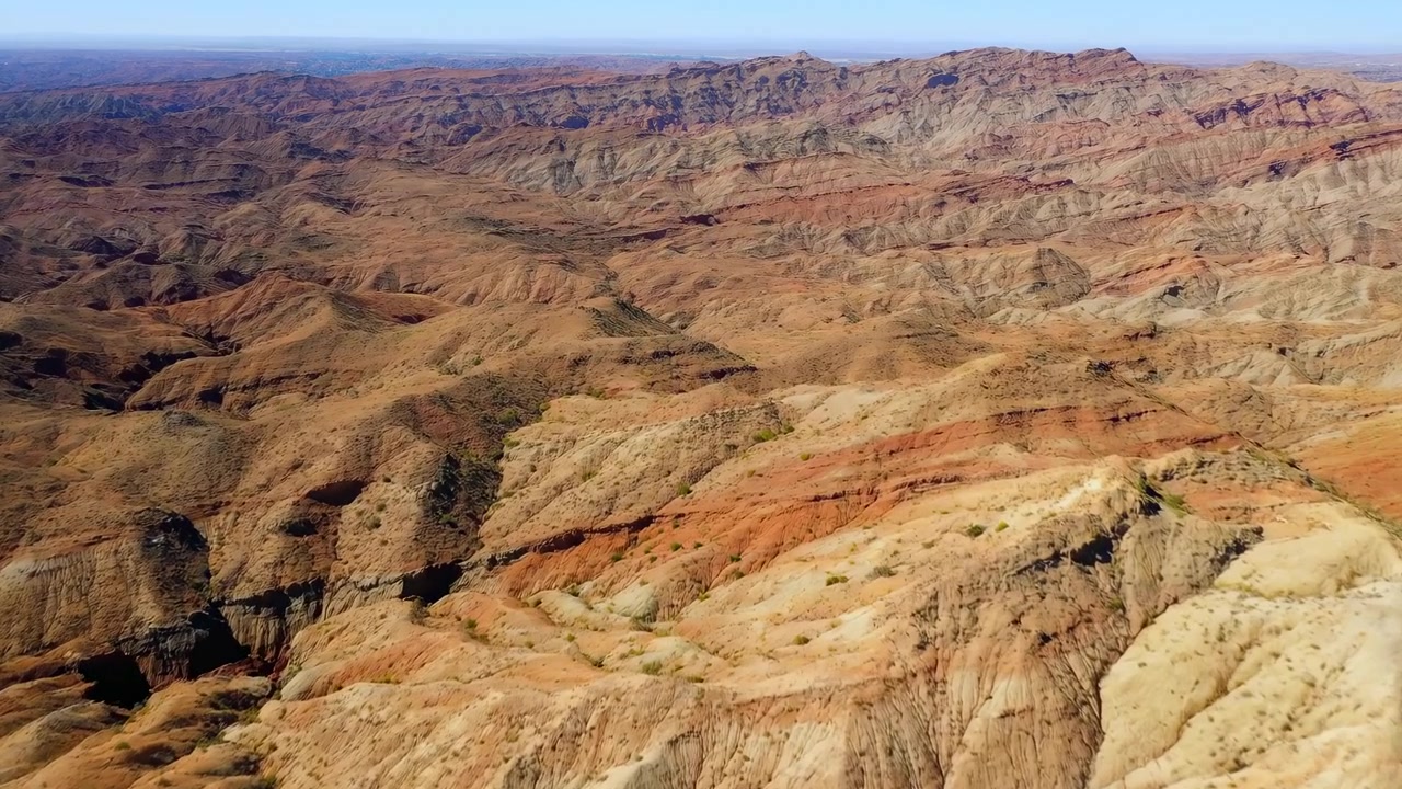 Aerial Red Canyon Desert Panorama Showing Layered Sandstone Ridges, Eroded Gullies And Ochre Slopes Under Warm