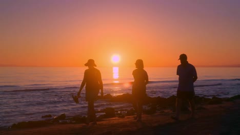 Sun-shining-over-the-sea-with-silhouette-of-people-passing-by