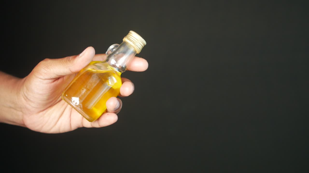Mano che tiene una piccola bottiglia di vetro con liquido giallo