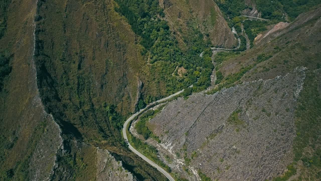 Drone flight reveals a winding, challenging road alongside a river through sharp mountain peaks in Colombia.