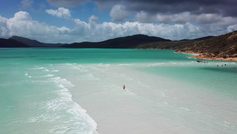 hombre caminando en el océano en las islas whitsundays, revelando un disparo de un dron