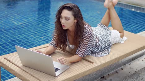 Focused-female-browsing-laptop-near-water