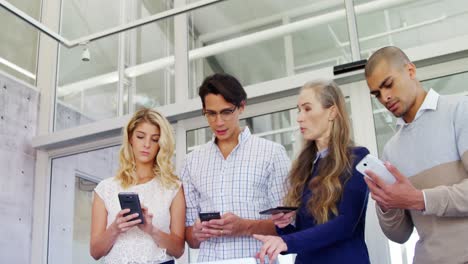 Colleagues-discussing-over-laptop-while-using-mobile-phone-4k