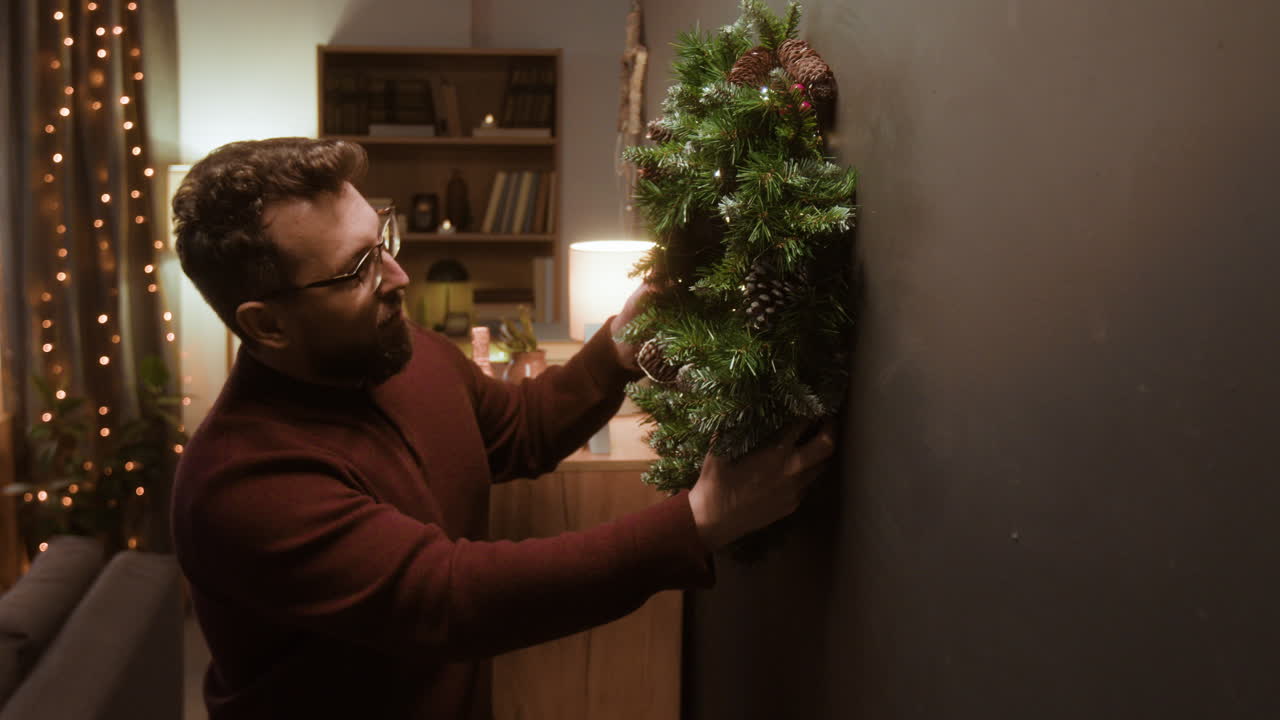 Man hanging a christmas wreath on the wall