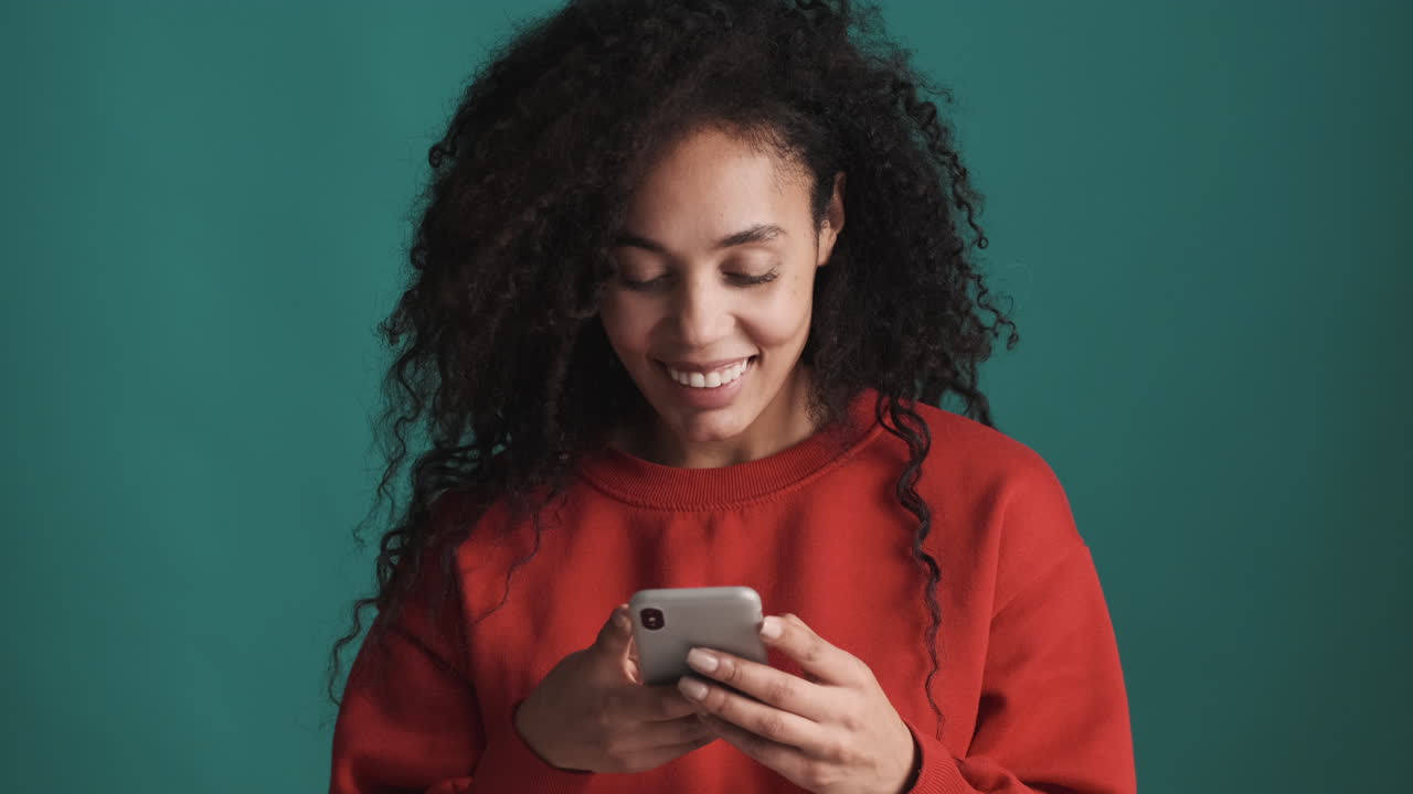 African american happy woman using smartphone over blue background.