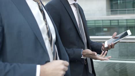 cropped shot of businessmen using tablet pc on street