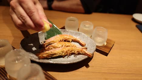 person squeezing lemon on grilled shrimp dish