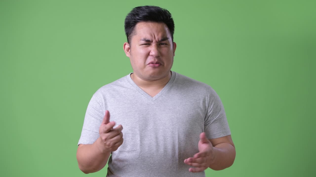 초록색 배경에 젊은 잘생긴 과체중 아시아인