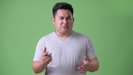 초록색 배경에 젊은 잘생긴 과체중 아시아인