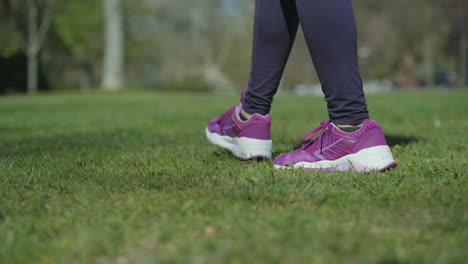 Slim-female-legs-in-black-leggings-walking-on-grass-in-park