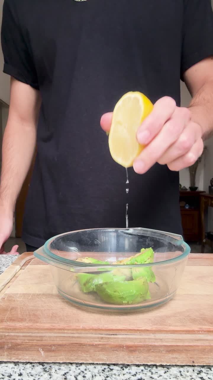 Squeezing fresh lemon juice over the pulp of an avocado