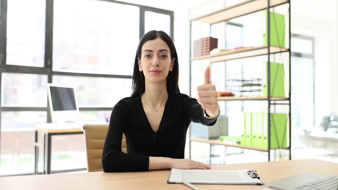 Businesswoman giving thumbs up in modern office