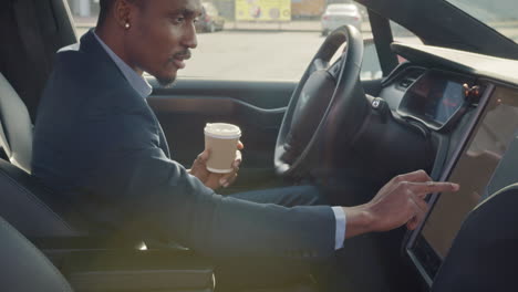 businessman driving an electric car and using touchscreen