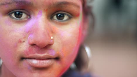 indian women close-up of face smeared with bright holi colors