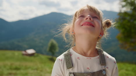 Portrait-little-girl-looking-at-sky-standing-meadow.-Cute-lady-smiling-on-camera