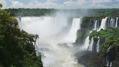 misty rough crashing waterfalls in rough flowing river hidden in valley in nature filled green jungle, splashing water from aggressive streams from cliffs in iguacu falls, brazil, south america