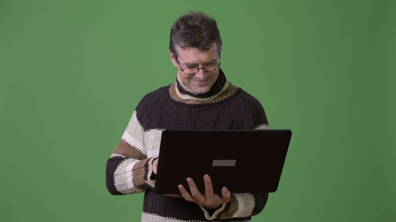 hombre guapo maduro con suéter de cuello alto contra un fondo verde