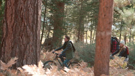 Amigos-Andando-En-Bicicleta-En-El-Bosque,-Vista-Lateral,-Panorámica-De-Derecha-A-Izquierda.