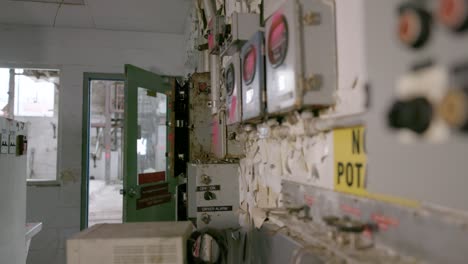 a pan shot of a worn-down control room with paint peeling off the walls in an abandoned factory