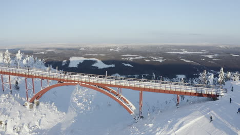 Drone-shot-of-a-big-frozen-bridge-with-a-lot-of-snow-on-it-during-a-cold-winter-at-a-ski-resort-in-Branäs,-Sweden