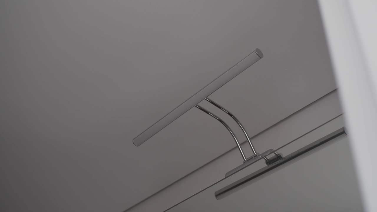 A modern metallic wall lamp illuminates a plain interior