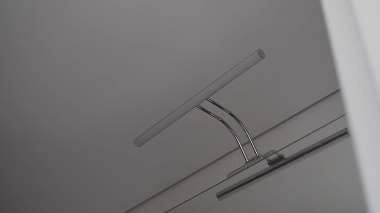 A modern metallic wall lamp illuminates a plain interior