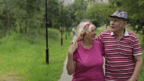 una pareja caucásica anciana caminando en el parque abrazándose. un hombre anciano camina con una mujer. marido, esposa
