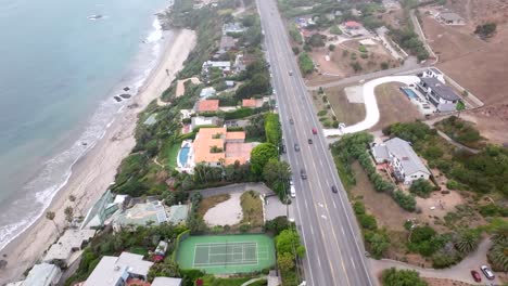 the pacific coast highway and waterfront mansions on the beach - aerial flyover