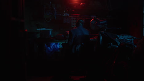 people working late at night in a dark room with red and blue lights.