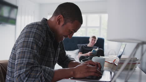 two male college students in shared house bedroom studying together