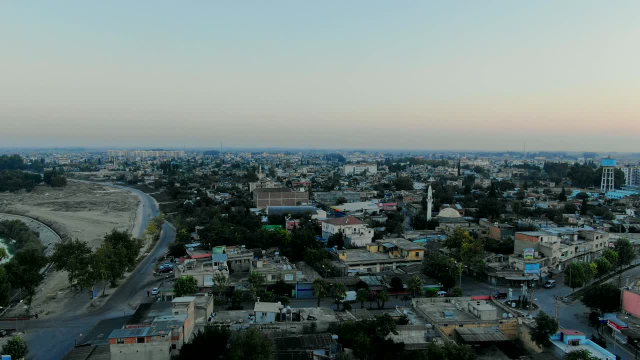 Flight above Muslim town with mosque minaret and residential buildings.