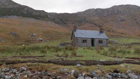 Ein-Langsamer-Schwenk-Nach-Links-Zeigt-Ein-Altes-Steingebäude-Vor-Einer-Bergkulisse-Im-Schottischen-Hochland-Entlang-Der-Küste-Von-Loch-Gleann-Dubh